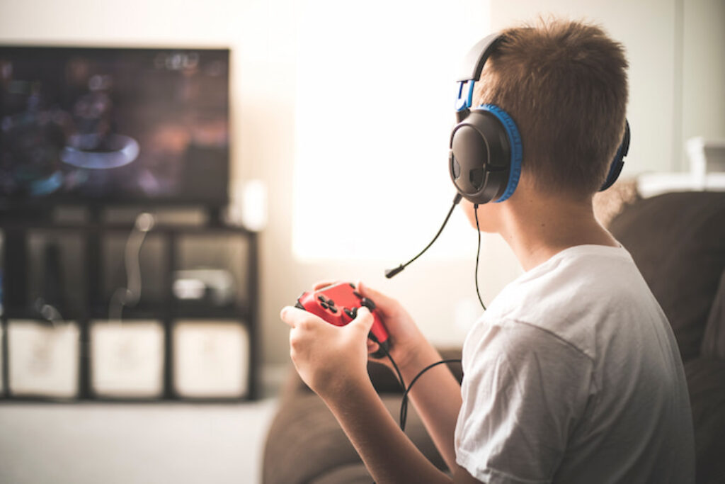 Criança jogando com um controle da Xbox e headset