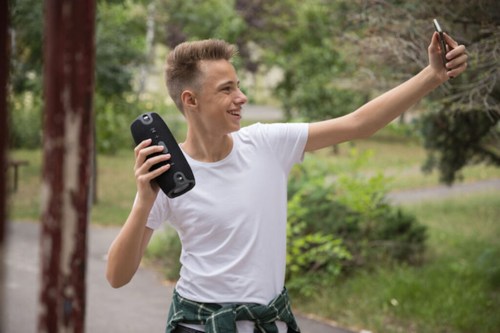 Garoto tirando uma selfie dele segurando uma caixa de som