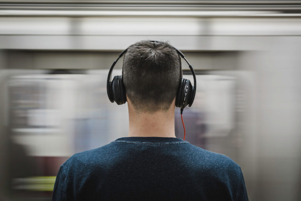 Homem ouvindo música no metrô com um headphone