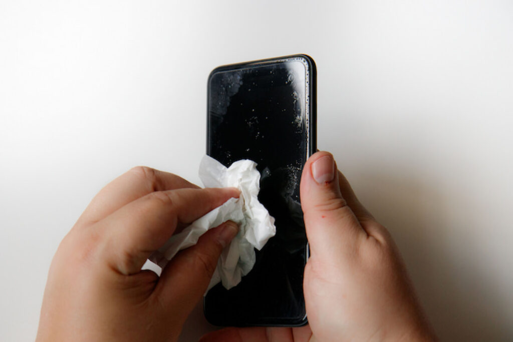 Pessoa limpando o celular com um pano pequeno