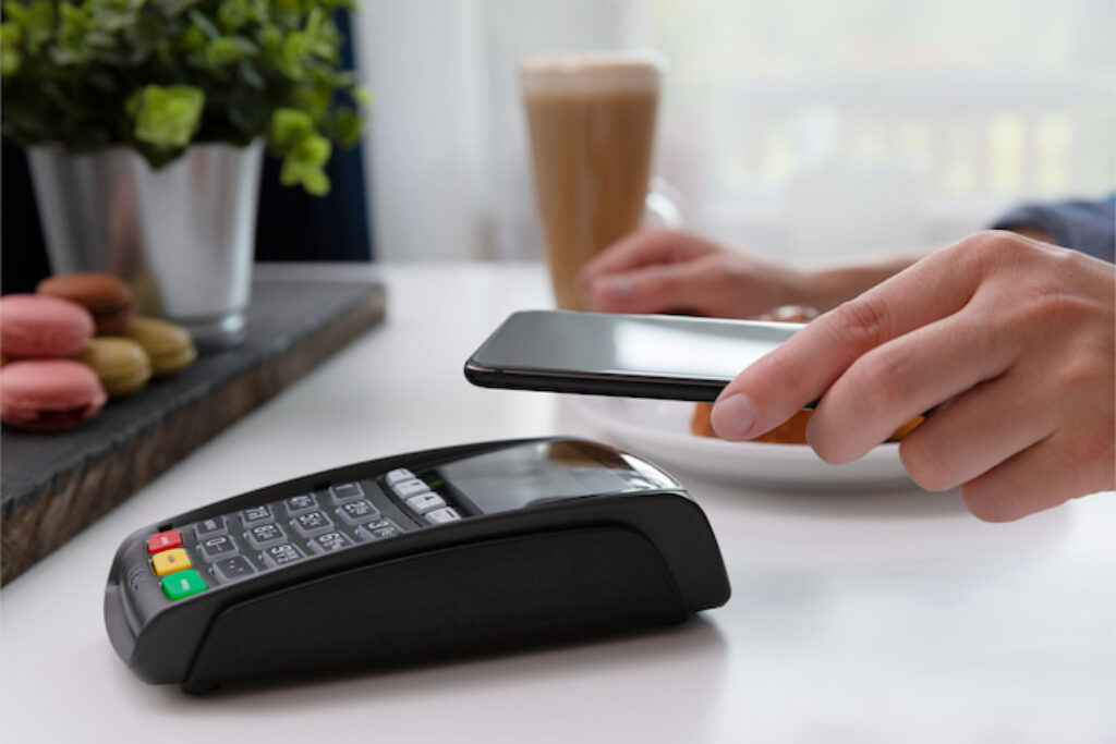 Pessoa usando a função NFC do celular para pagar na maquininha de cartão