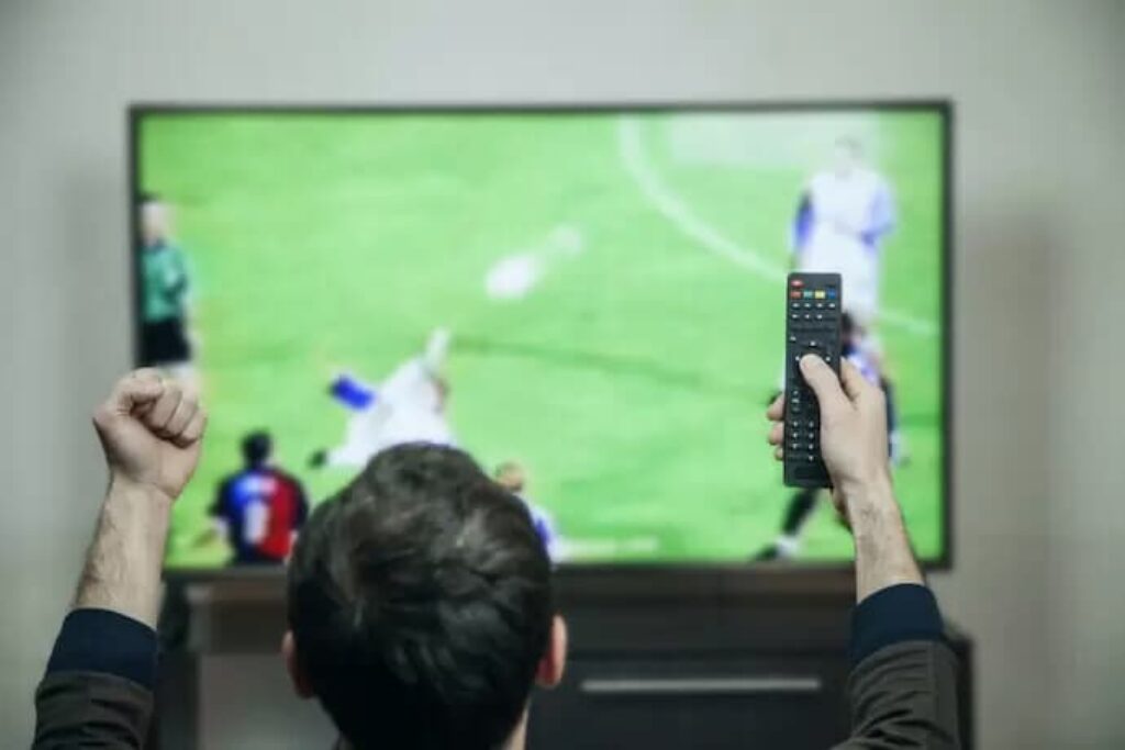 Homem vendo jogo de futebol em TV para ser usada como monitor