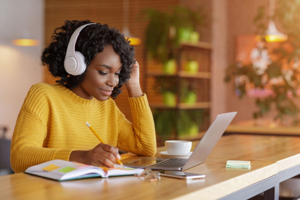Mulher estudando com fone de ouvido ligado no notebook