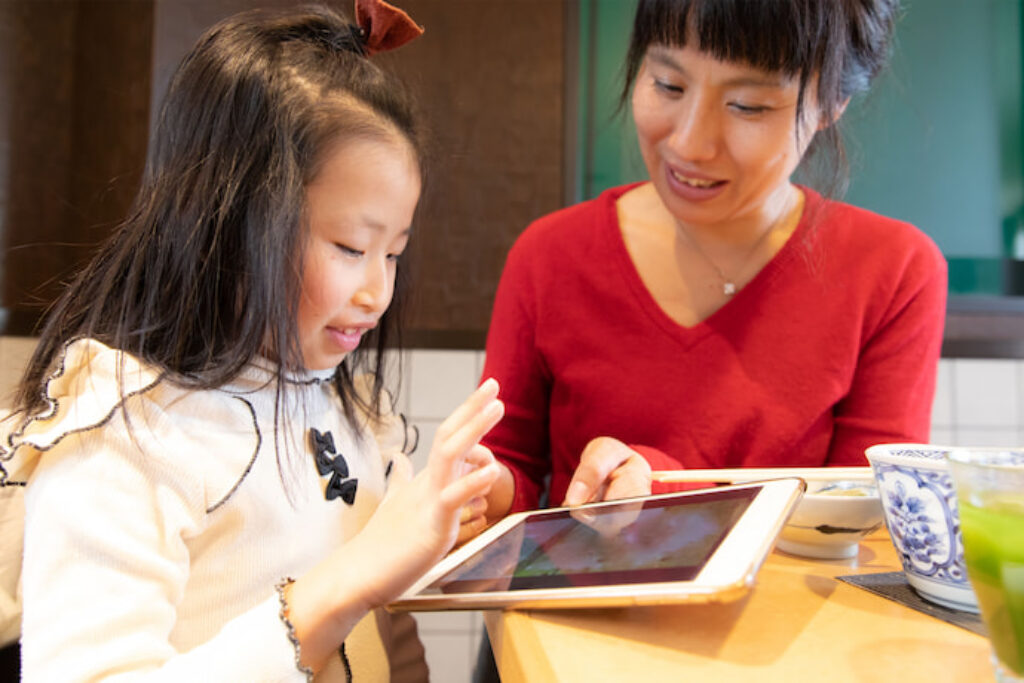 Criança usando o tablet com a mãe