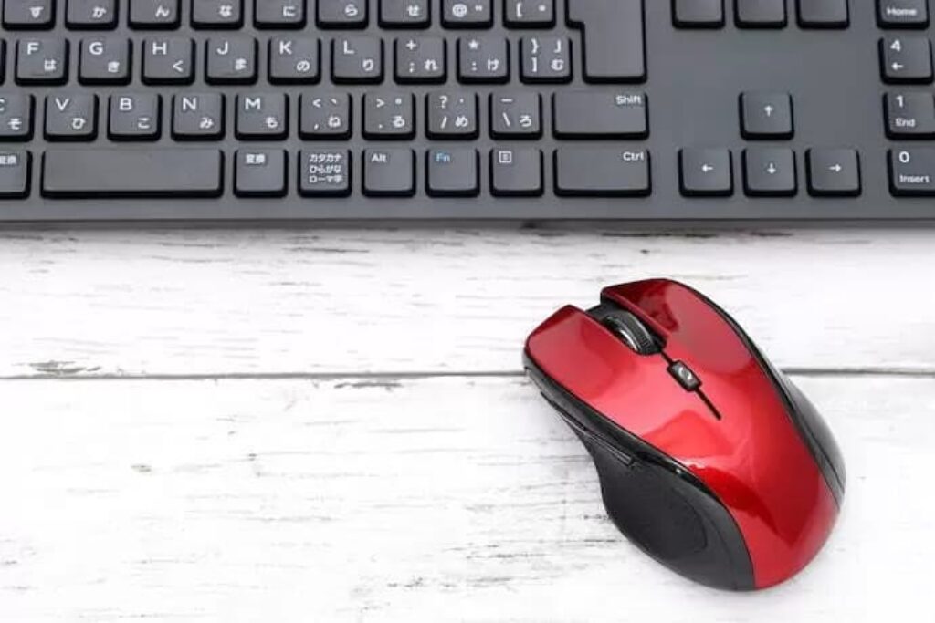 teclado preto e mouse vermelho sem fio em um fundo branco
