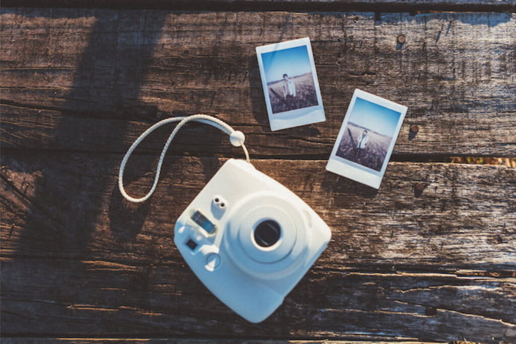 Câmera Polaroid na mesa com duas fotos reveladas